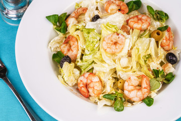Mediterranean salad. Cabbage, tomatoes, shrimps, olives, olives, basil and rosemary, seasoned with olive oil