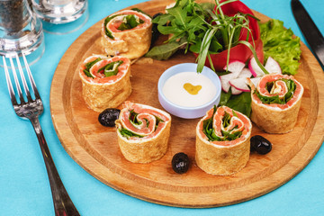 Mediterranean snack. Rolls with salmon, greens, cucumber and vegetables with cream sauce