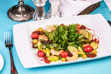 Mediterranean salad with grilled shrimps, cherry tomatoes, arugula, greens, avocado, lime, olives, balsamic sauce
