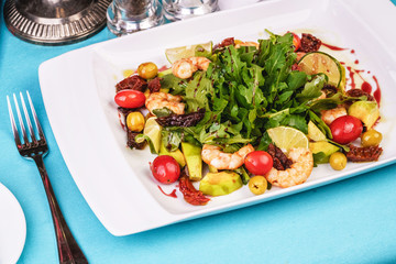 Mediterranean salad with grilled shrimps, cherry tomatoes, arugula, greens, avocado, lime, olives, balsamic sauce