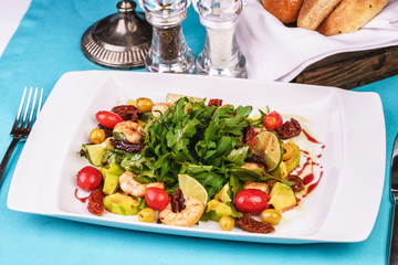 Mediterranean salad with grilled shrimps, cherry tomatoes, arugula, greens, avocado, lime, olives, balsamic sauce