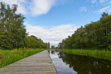 Naklejka premium The Forth and Clyde canal, part of Scotlands waterways Heritage near the Falkirk Wheel with Narrow Boats moored along the Bank in the distance, Falkirk, Scotland.