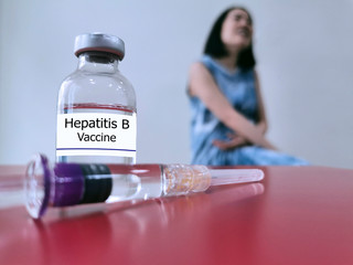 Bottle of Hepatitis B vaccine (selective focus) for injection and blurred background of woman. This...