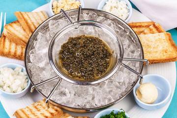 Mediterranean caviar appetizer on ice, toast, butter, greens and a set of sauces