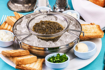 Mediterranean caviar appetizer on ice, toast, butter, greens and a set of sauces