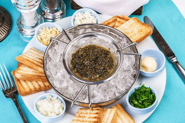 Mediterranean caviar appetizer on ice, toast, butter, greens and a set of sauces