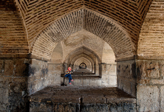 Woman sitting inside The Khaju Bridge, Isfahan, Iran