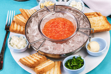 Mediterranean red caviar appetizer on ice, toast, butter, and a set of sauces