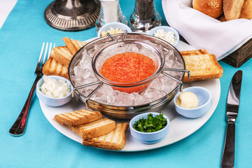 Mediterranean red caviar appetizer on ice, toast, butter, and a set of sauces