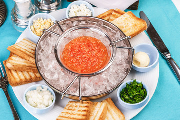 Mediterranean red caviar appetizer on ice, toast, butter, and a set of sauces