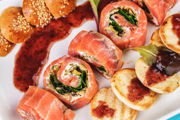 Mediterranean salmon rolls with cheese and greens in chili sauce, served with pancakes and buns