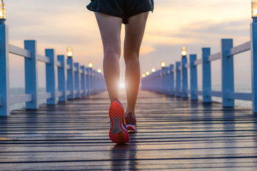 legs of healthy woman jogging alone at daily morning on the wooden jetty bridge or pier, daily...