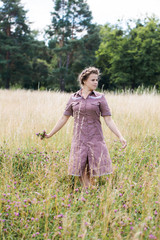 Young beautiful woman in a dress dancing in the field