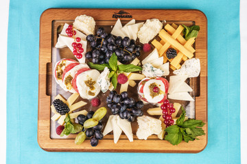 European snack. Champagne with fruit plate, berries, and cheese. Black and green grapes, cheese platter, red and black currants, mint, lingonberries.