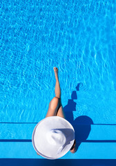 Beautiful woman with a white hat is relaxing in an infinity pool
