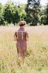 beautiful woman in country style dress in the field, view from the back