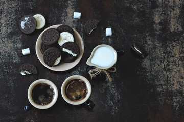 Obraz na płótnie Canvas Two cups espresso, a jug of milk and chocolate milk cookies. Breakfast concept on dark stylish background.