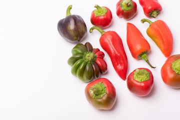 Several ripe sweet and hot peppers of red and orange on a white background