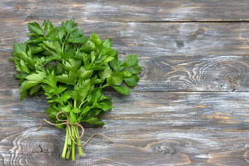 Bunch of fresh organic celery on a wooden background, top view, free space