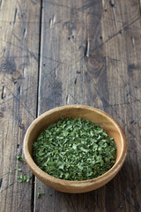 Dried green celery in a wooden bowl on a wooden table, top view, free space