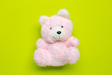 Toy pink bear on green background.