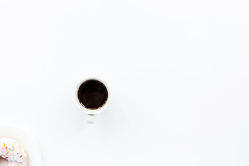 donut and black coffee with copy space. Cup of black coffee with donut on a plate on white table, top view, flat lay. Delicious breakfast.