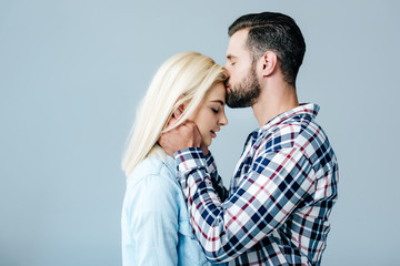 handsome man kissing beautiful young woman isolated on grey