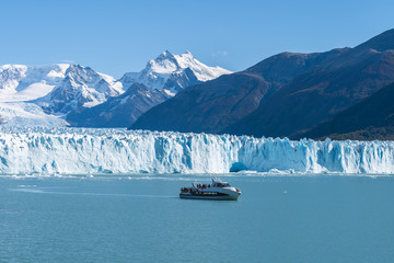 Ferry boat in front of Perito Moreno glacier, blue ice burg glacier from peak of the mountain through the blue lake in Los Glaciares National Park, Santa Cruz, Argentina, southern Patagonia ice field