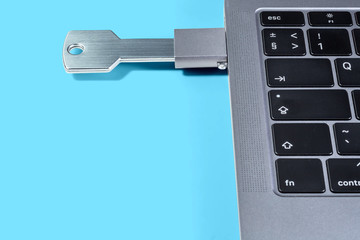 USB-drive in the form of a key through the adapter connected to a modern laptop on a blue...