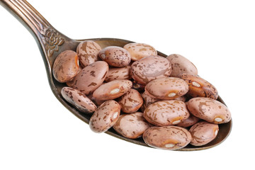 In the old golden spoon there is a small pile of food - dry brown spotted beans isolated macro