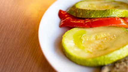 grilled vegetables, red sweet paprika and zucchini on white plate on the wooden table in restaurant. Selective focus. Horizontal with copy space. Healthy food, dietary