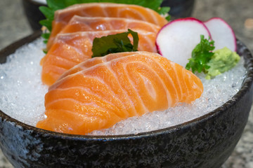 salmon sashimi on ice in black bowl japanese food
