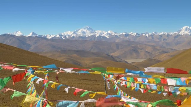 SLOW MOTION, CLOSE UP: Colorful buddhist prayer flags flutter in the desert leading to Mount Everest. Cinematic shot of multicolored pieces of cloth flapping in winds blowing across Tibetan plains.