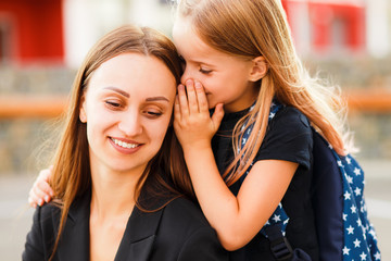 Mom leads her daughter to school. Return to school. Woman and girl with backpack behind the back. Beginning of lessons. First day of fall.