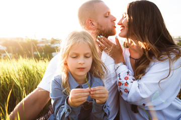 Happy family with blonde daughter smiling and hugging in nature.