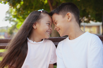 Close up of happy cute little kids smiling, touching with their foreheads. Adorable Asian brother and sister cuddling outdoors. Happy healthy kids having fun in the park
