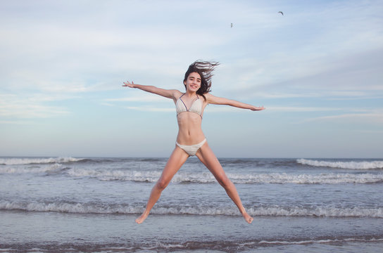 Smiling teenage girl jumping in the air on beach, Argentina