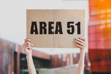 Area 51on a paper banner in men's hand. Human holds a cardboard with an inscription: Area 51