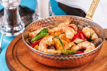 Seafood, Mediterranean cuisine, European dish. Warm salad of grilled fish pieces, shrimps and mussels in a frying pan, with grilled vegetables - with green onions, greens, mushrooms and vegetables.