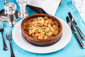 Mediterranean dish, European cuisine. Seafood stew soup- shrimp, fish meat and mushrooms, with cheese and greens