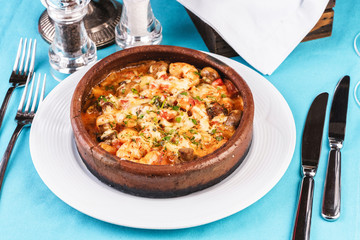 Mediterranean dish, European cuisine. Seafood stew soup- shrimp, fish meat and mushrooms, with cheese and greens