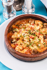 Mediterranean dish, European cuisine. Seafood stew soup- shrimp, fish meat and mushrooms, with cheese and greens