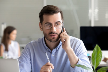 Focused businessman consulting client by phone at workplace