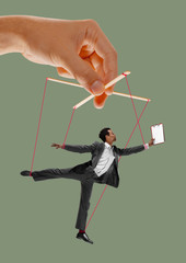 Man like a puppet in somebodies hands on green background. Concept of unfair manipulation,...
