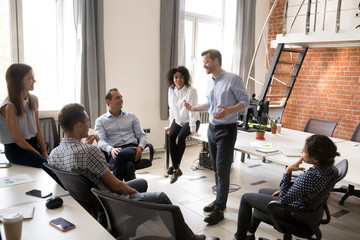 Confident male leader, coach talking with group of office workers