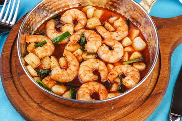 Seafood, Mediterranean cuisine, European dish. Warm salad of grilled fish pieces, shrimps and mussels in a frying pan, with grilled vegetables - with green onions, greens, mushrooms and vegetables.