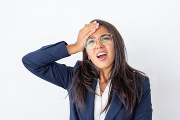 Shocked businesswoman with hand on forehead. Unhappy young businesswoman in eyeglasses holding hand...
