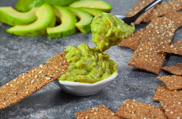 Guacamole in a bowl on a background of sliced avocado.