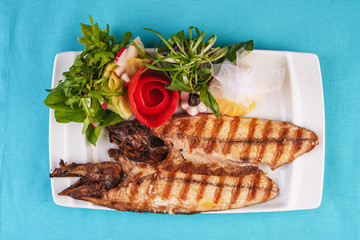 Seafood, Mediterranean cuisine. Grilled Seafood Steak fish with greens, cucumber, lemon and chili. Japanese food