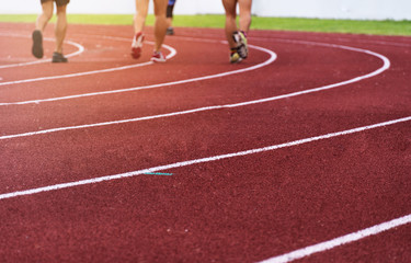 blur group of athlete legs on red running tract white curve line of sport stadium background